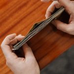 Resource Allocation - Close-up of hands counting currency with coins scattered on a wooden table. Perfect for finance and business themes.