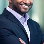 SMART Goals - Portrait of a confident businessman in a suit, smiling and posing indoors.