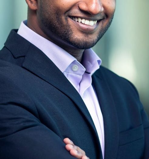 SMART Goals - Portrait of a confident businessman in a suit, smiling and posing indoors.