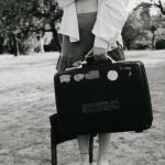 Balanced Scorecards - A woman with a suitcase stands on a chair in an outdoor setting.