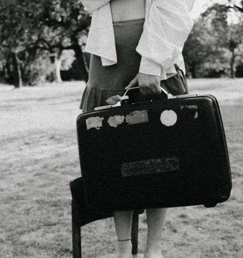 Balanced Scorecards - A woman with a suitcase stands on a chair in an outdoor setting.