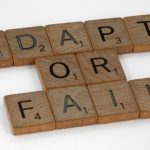 Change Management - Scrabble tiles spell 'Adapt or Fail' on a white background, conveying a motivational message.