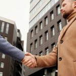 Partnerships - Man and woman shaking hands in a cityscape setting, symbolizing a business partnership.