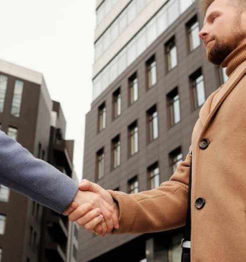 Partnerships - Man and woman shaking hands in a cityscape setting, symbolizing a business partnership.