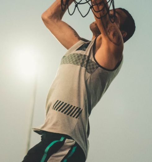 Competitive Advantage - Athlete performs a powerful dunk on an outdoor basketball court at dusk.