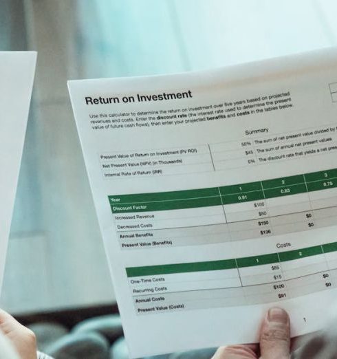 Risk Assessment - Close-up of two individuals analyzing financial documents related to return on investment.