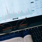 Risks - Close-up of laptop screen with business analytics, book, and eyeglasses.