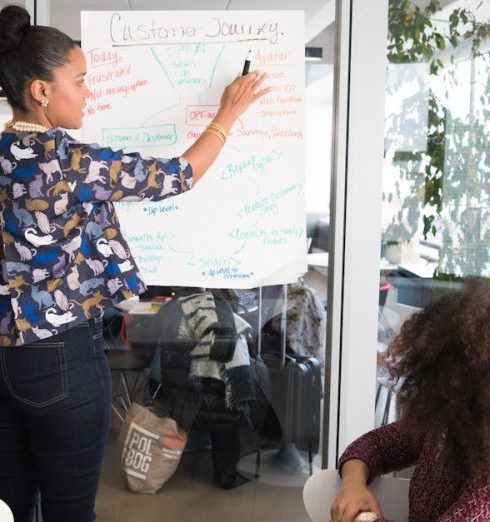 Business Strategy - Two women collaborating on project strategy using notes in modern office.