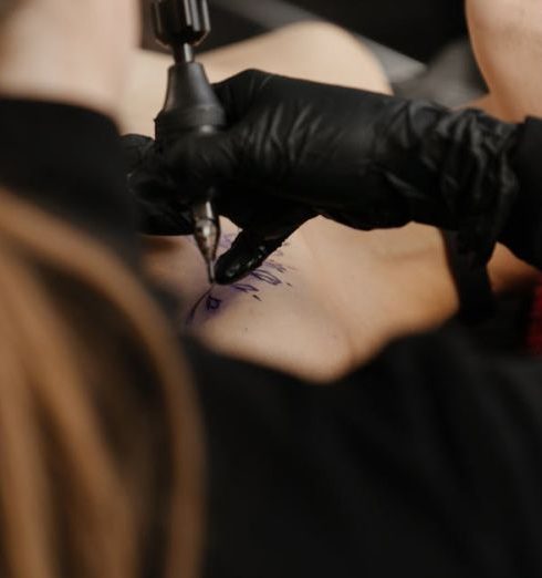 Regulatory Risks - A skilled tattoo artist focuses on creating a design on a client's shoulder in a modern tattoo studio.