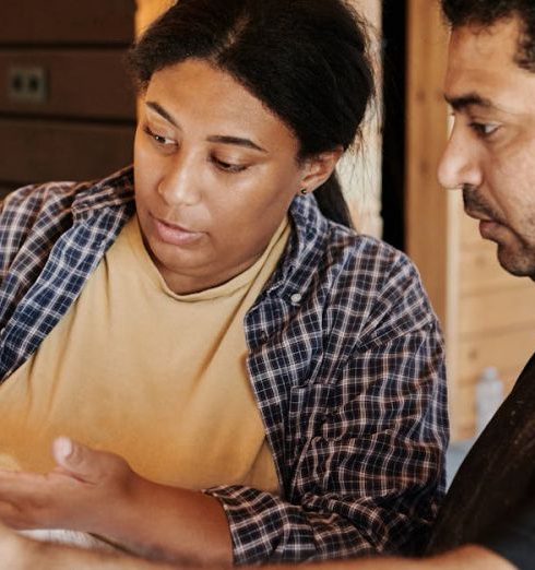 Safety Plan - Two construction professionals examining blueprints in a wooden building interior.