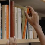 Human Resource Risks - A person choosing a book from a library shelf showing diverse literature collection.