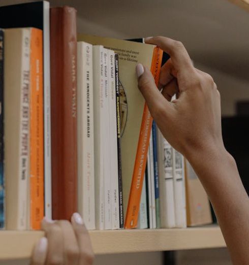 Human Resource Risks - A person choosing a book from a library shelf showing diverse literature collection.