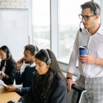 Employee Training - A diverse group of employees working together in a bright, modern call center with headsets.