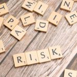 Risk Indicators - Scrabble tiles spelling out 'risk' scattered on a rustic wooden background, symbolizing uncertainty.