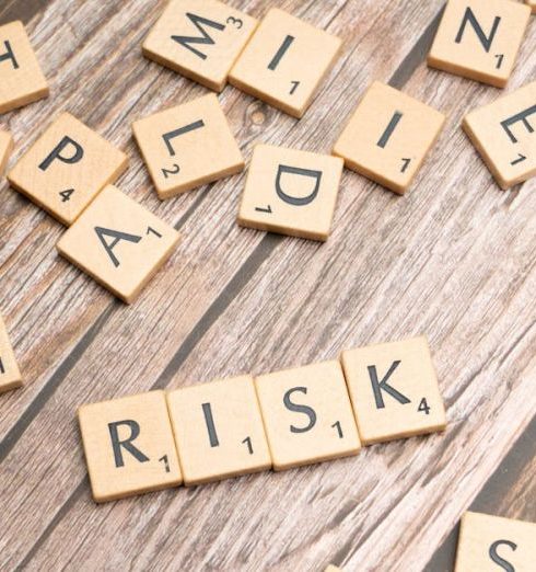 Risk Indicators - Scrabble tiles spelling out 'risk' scattered on a rustic wooden background, symbolizing uncertainty.