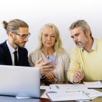 Insurance - Three individuals collaborating on financial documents during a business meeting.