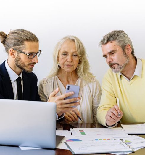 Insurance - Three individuals collaborating on financial documents during a business meeting.