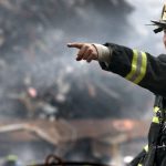 Natural Disaster - A firefighter in action at a disaster scene, directing rescue operations amidst smoke and debris.