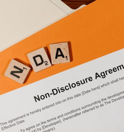 Intellectual Property - Top view of a Non-Disclosure Agreement with NDA in Scrabble tiles, emphasizing confidentiality.