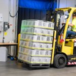 Operations - A warehouse employee operating a forklift to move stocked goods indoors. Perfect for industry and logistics visuals.