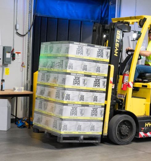 Operations - A warehouse employee operating a forklift to move stocked goods indoors. Perfect for industry and logistics visuals.