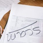 Risk Audits - Close-up of hands reviewing suspicious tax documents labeled 'scam' on a desk.