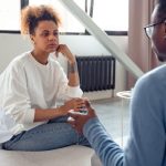 Feedback - Two individuals engaged in a thoughtful therapy session indoors.