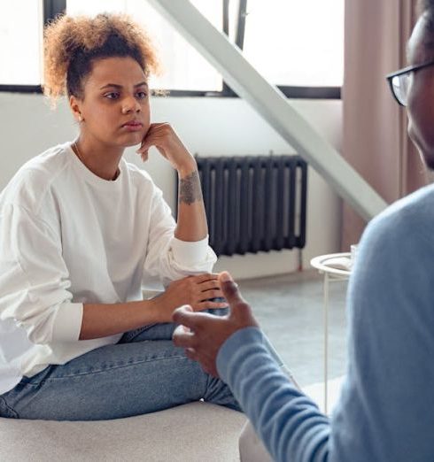 Feedback - Two individuals engaged in a thoughtful therapy session indoors.