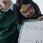 Recognition Programs - Two young men celebrate winning an IT contest holding a large check.