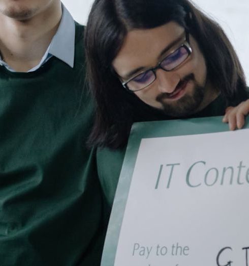 Recognition Programs - Two young men celebrate winning an IT contest holding a large check.