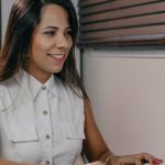 Employee-Centric - Professional woman in white shirt using computer at desk in modern office setting.