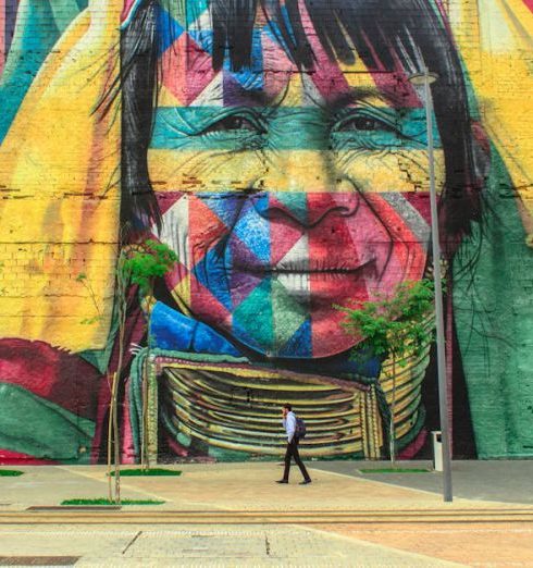 Culture - Colorful mural depicting a native face on an urban street wall with a passerby.