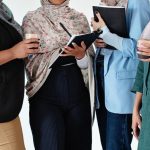 Team-Building - A group of diverse Muslim women in hijabs working together in an office setting.