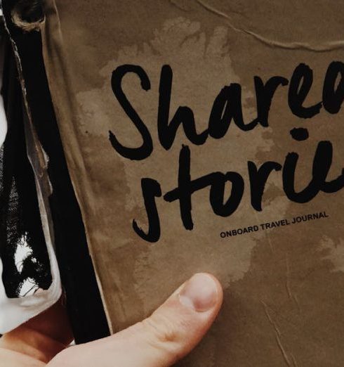 Storytelling - Hand holds a "Shared Stories" journal against a blurred outdoor backdrop, emphasizing creativity and personal storytelling.