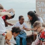 Initiative - A group of children volunteering to clean a beach with a 'Save the Earth' sign.