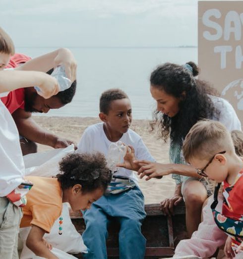 Initiative - A group of children volunteering to clean a beach with a 'Save the Earth' sign.