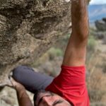 Challenges - Man in red shirt bouldering on a steep rock face, showcasing strength and determination.