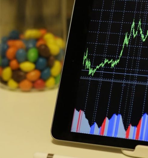 Analytics - Tablet display of stock market data with smartphone and colorful candies on desk.