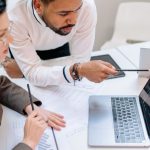 Predictive Analytics - Business professionals discussing data at a desk with a laptop.