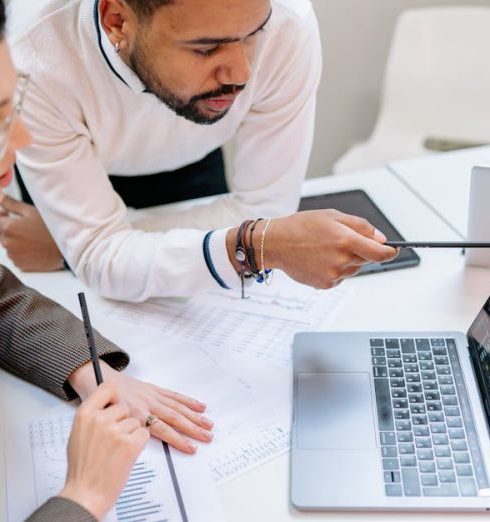 Predictive Analytics - Business professionals discussing data at a desk with a laptop.