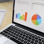 Data Analysis - Laptop displaying charts and graphs with tablet calendar for data analysis and planning.