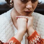 Competitive Analysis - A woman in a knitted sweater contemplating her next move in a chess game indoors.