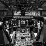 Dashboards - Black and white image of airplane cockpit showing instruments and controls.