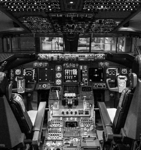 Dashboards - Black and white image of airplane cockpit showing instruments and controls.