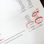 Data Accuracy - Financial statement with red annotations on a wooden table.