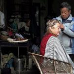 Customer Segmentation - An elderly person receives a haircut inside a rustic, cluttered home, creating a nostalgic atmosphere.