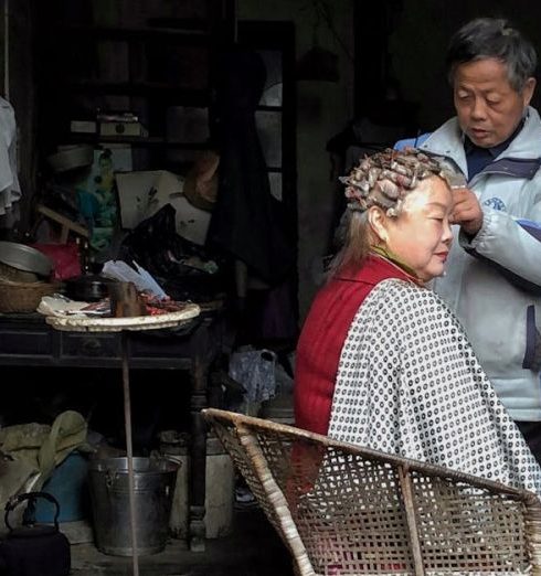 Customer Segmentation - An elderly person receives a haircut inside a rustic, cluttered home, creating a nostalgic atmosphere.