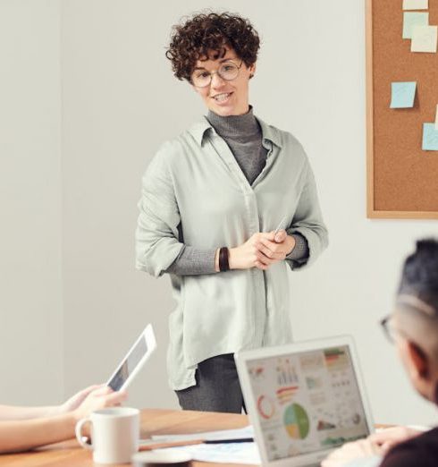 Employee Performance - Diverse team discussing ideas during an office meeting with charts displayed on laptops.