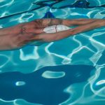 Performance Improvement - A male swimmer in a swimming pool, captured underwater, practicing his technique.