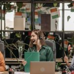 International Office - Three women with headsets working together in a vibrant, plant-filled modern office space.